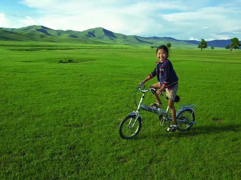 A little girl on her bike in the middle of the Mongolian steppes
