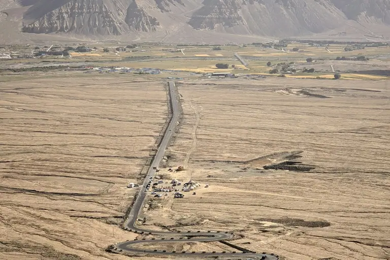 a road in the middle of a desert with mountains in the background
