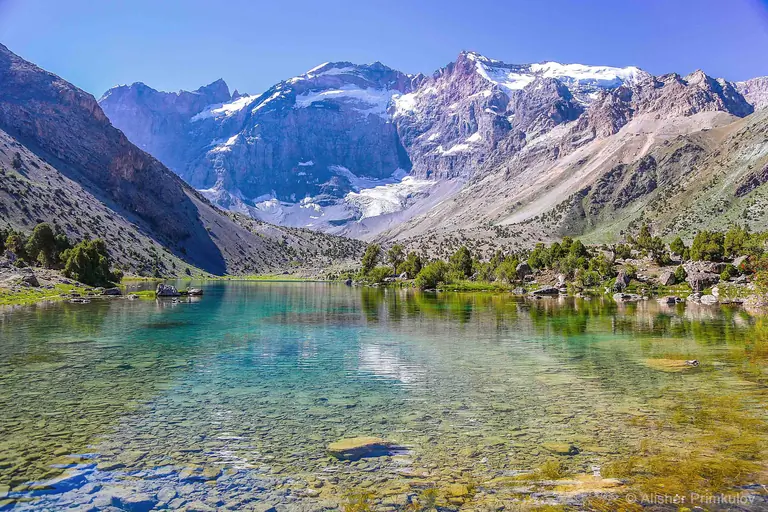 A beautiful lake cristalin like a mirror reflecting surrounding mountains with spruces around