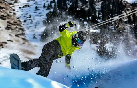 a man riding a snowboard down the side of a snow covered slope