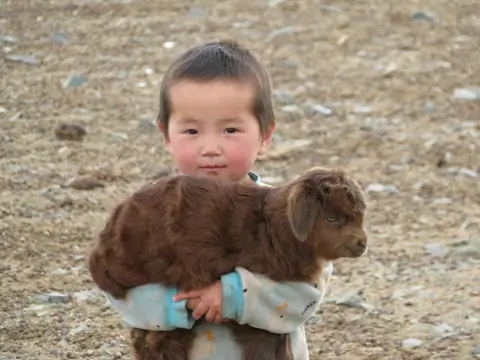 Kid with baby lamb, Mongolia