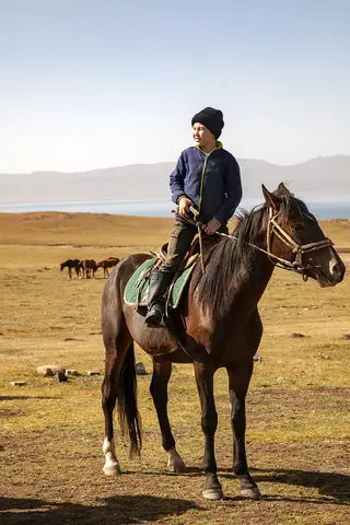 Young boy riding a horse in Son Kul img