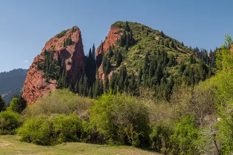 two large red rocks covered with fir trees look like a broken heart