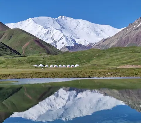 View of the yurt camp on the foot of peak Lenin reflecting in the Tulpar Kel lake