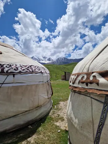 Two white yurts at the foot of peak Lenin