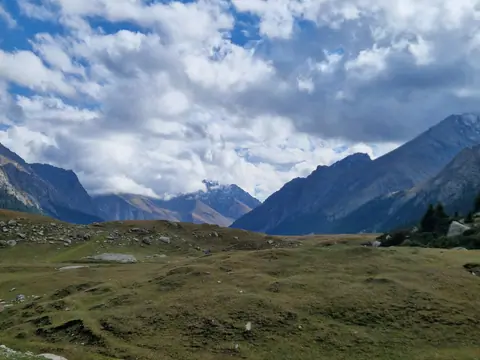 The valley of Turgen Ak-Suu in autumn, surrounding by high peaks, green pastures for nomads