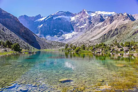 A beautiful lake cristalin like a mirror reflecting surrounding mountains with spruces around