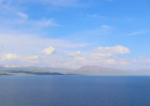 View from the West shore of the Song Kul lake, here the White stone mount seems red backside of the blue of the lake