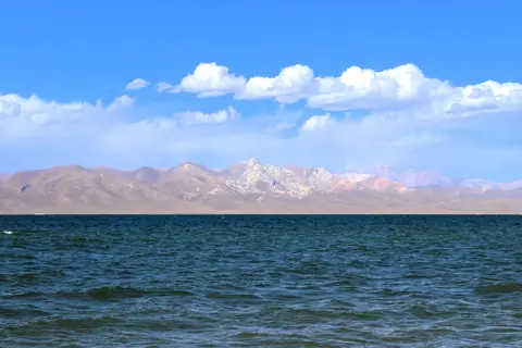 View of Ak-Tash mountain which means "White stone"  backside of the deep blue lake of Song Kul with blue sky and some with clouds