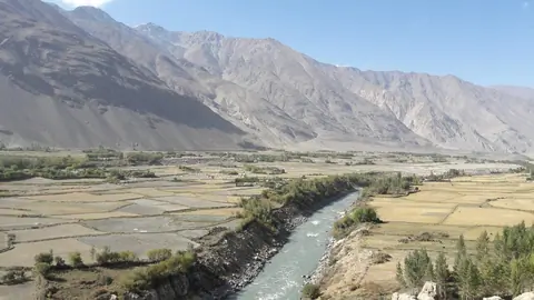 panoramic views unfold across the fertile floodplains below—patchworks of golden fields, poplar groves, and grazing livestock on both the Tajik and Afghan sides, from the Khakhka fortress