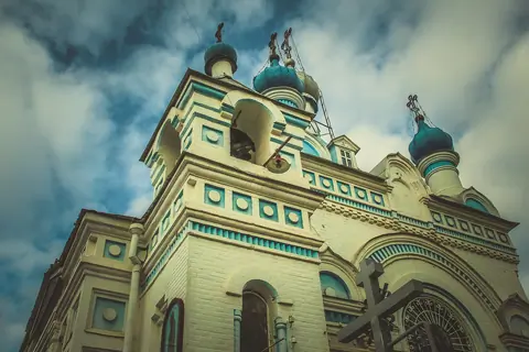 View of the main bell tower, painted in light blue and white, with a gilded onion dome at the top of the Cathedral of the Assumption of the Virgin in Tashkent