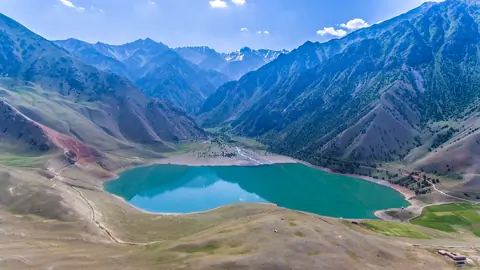 Turquoise mountain lake in a wide valley under a blue sky.