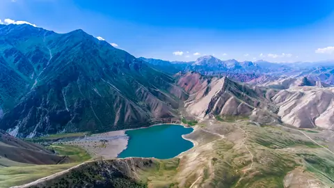 Mountain valley with a turquoise lake under a bright blue sky.