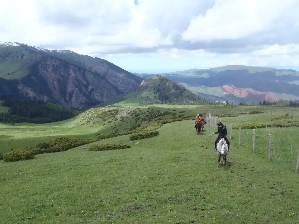 Horse riders riding from Kök Jayik meadows to Yrdyk meadows, we can see on the right side red rocks of Jeti Oguz "7 bulls"