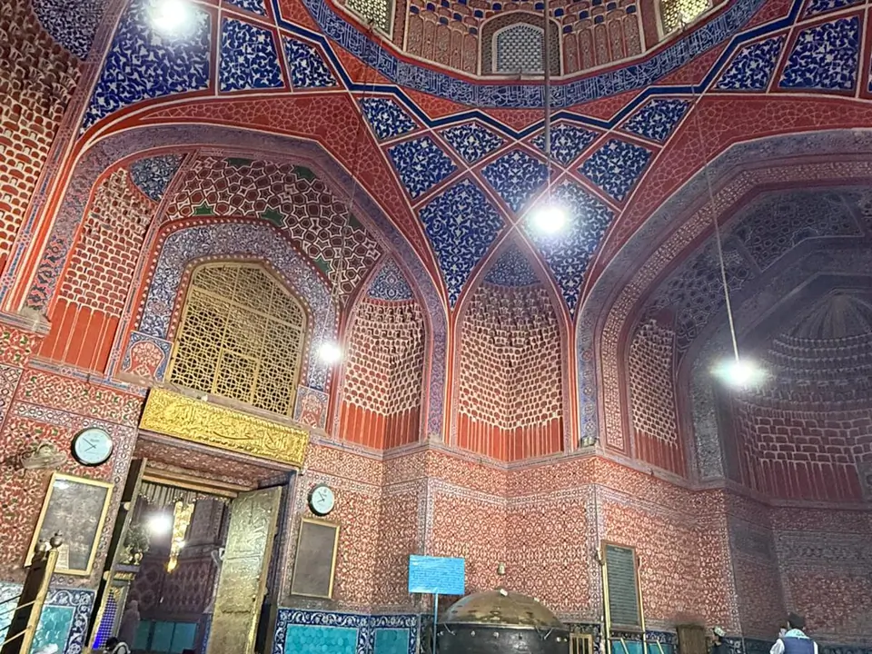 Interior of the coupole of the Blue Mosque, featuring high vaulted ceilings, intricately tiled walls in shades of blue and white, and a large prayer hall carpeted in red, with soft natural light filtering through arched windows.