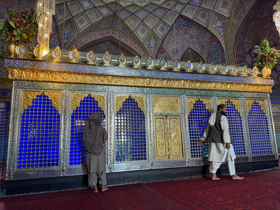 Interior of the Blue Mosque, featuring high vaulted ceilings, intricately tiled walls in shades of blue and white, and a large prayer hall carpeted in red, with soft natural light filtering through arched windows.
