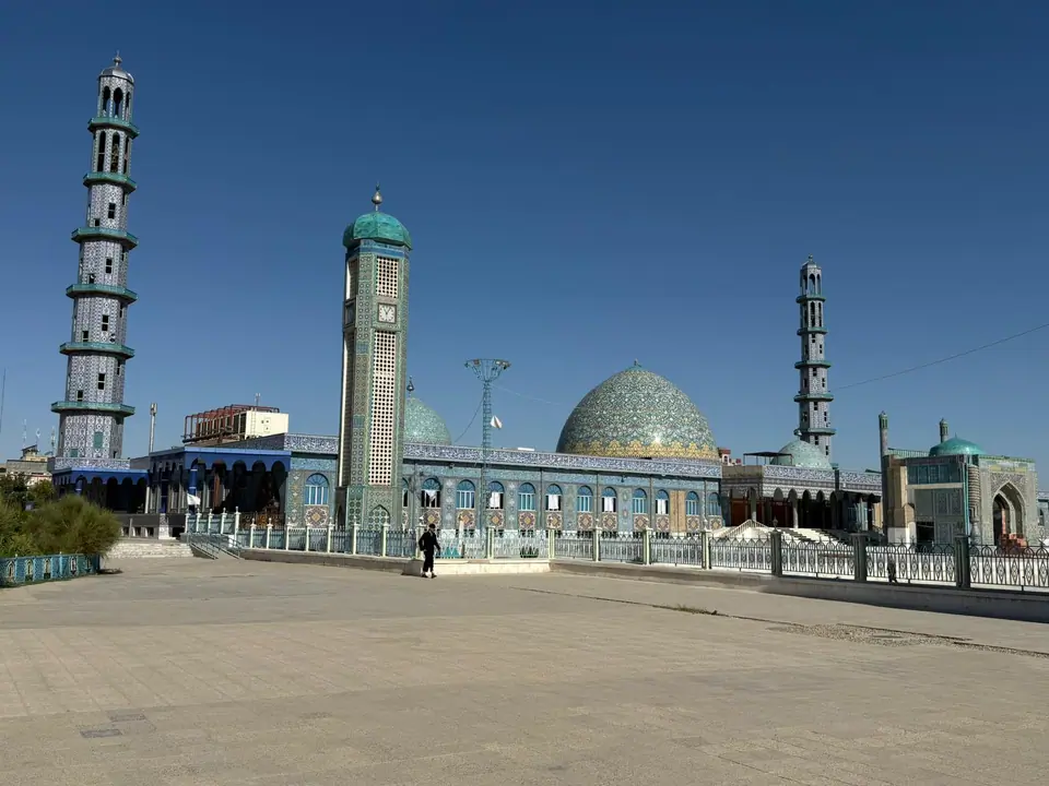 View of the Blue Mosque in Mazar-e Sharif, with its turquoise domes, arched entrances, and walls covered in intricate blue tilework.