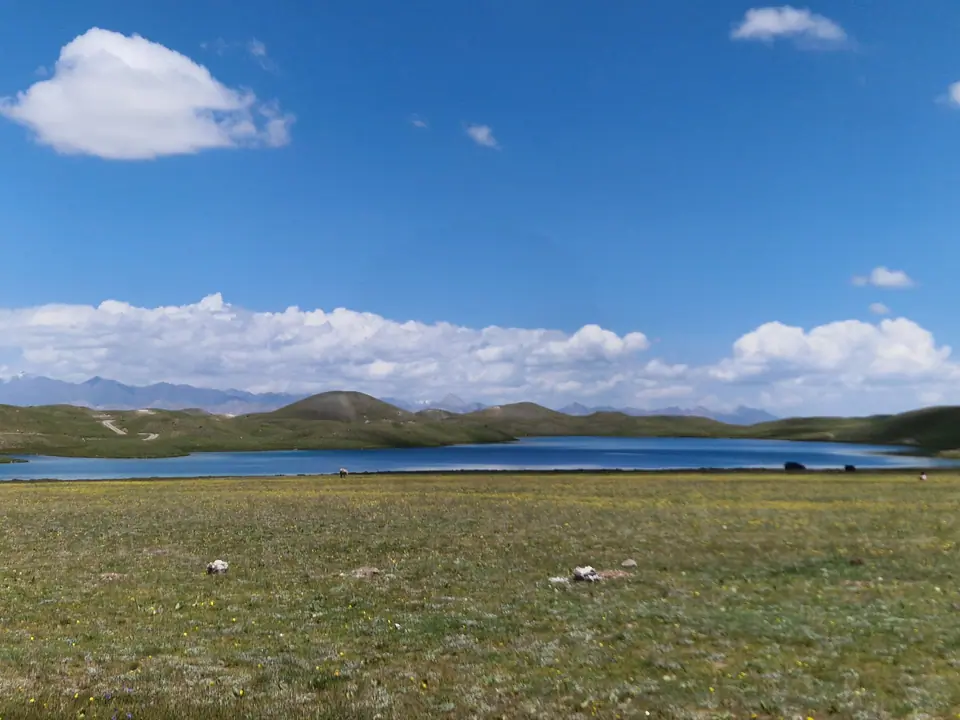 A turquoise blue lake surrounded by green meadows where Kyrgyz nomads set up their yurts in summer. The lake often reflects Lenin Peak, one of the 7,000-meter peaks of the Pamir Mountains.