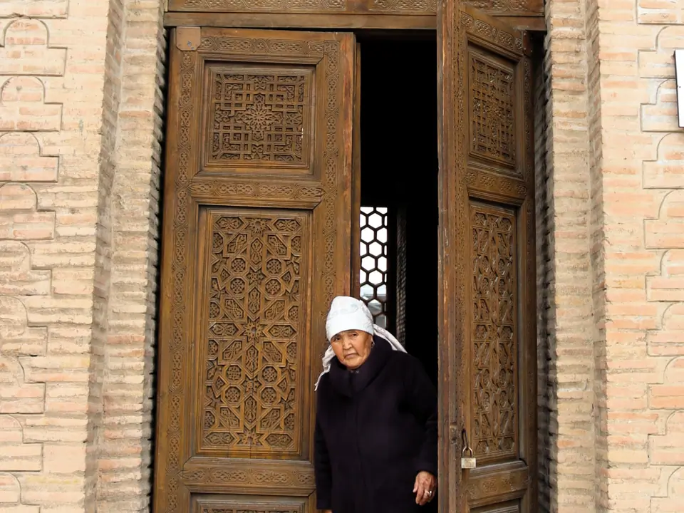 The wooden and carved door of the middle mausoleum of Uzgen with Kyrgyz woman