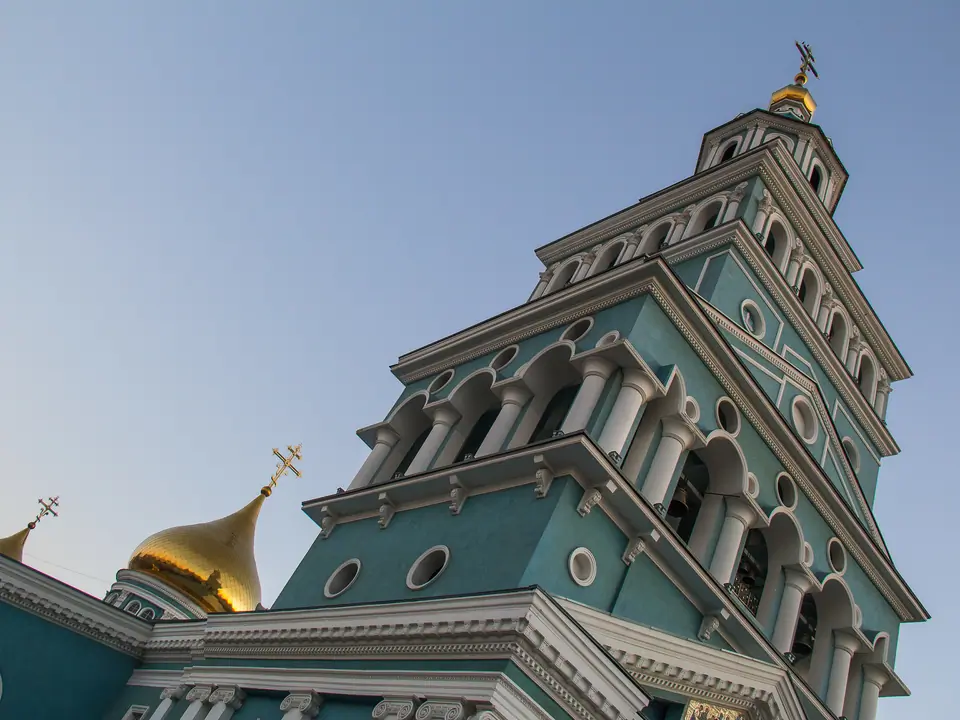 View of the main bell tower, painted in light blue and white, with a gilded onion dome at the top of the Cathedral of the Assumption of the Virgin in Tashkent