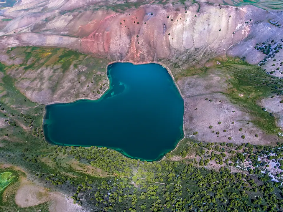 Aerial view of a deep blue lake surrounded by rocky, green hills.