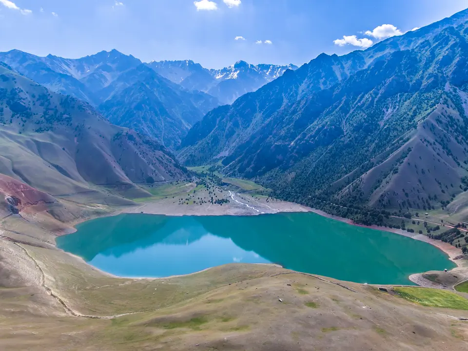 Turquoise mountain lake in a wide valley under a blue sky.
