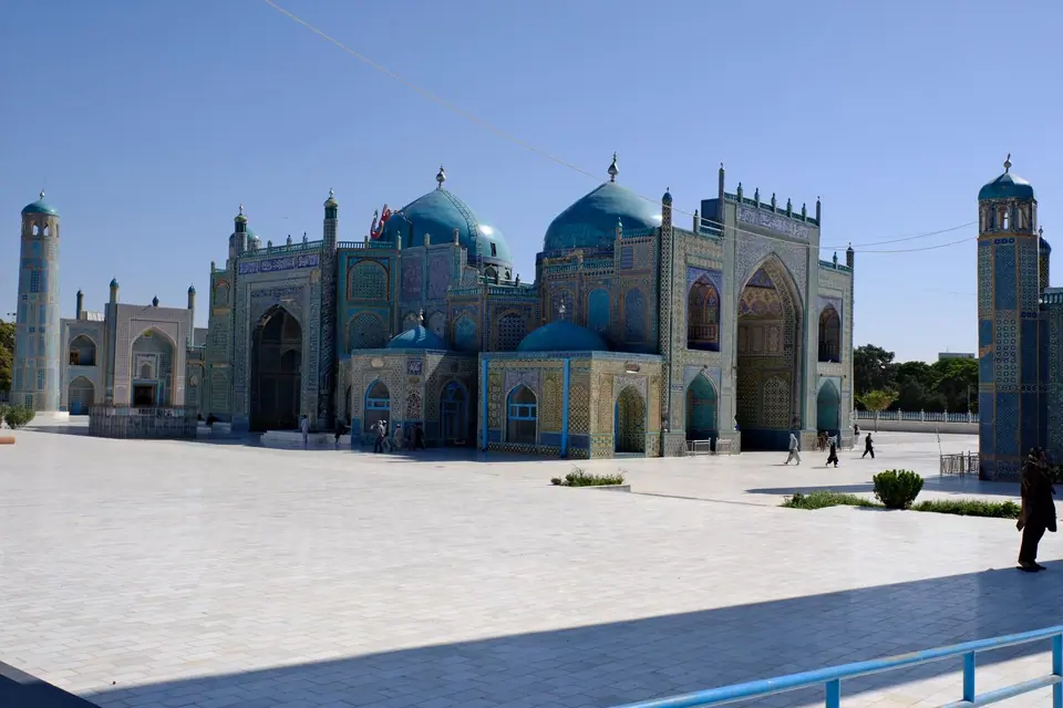 View of the Blue Mosque in Mazar-e Sharif, with its turquoise domes, arched entrances, and walls covered in intricate blue tilework.