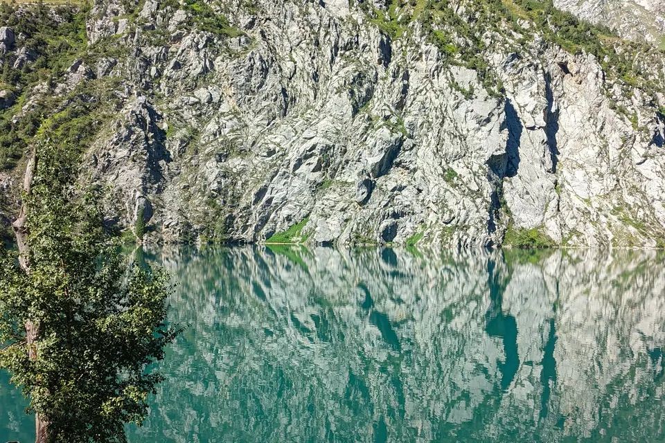 The cliff is reflectin into turquoise water of the Kara-Kamysh lake also known as Kara-Suu lake