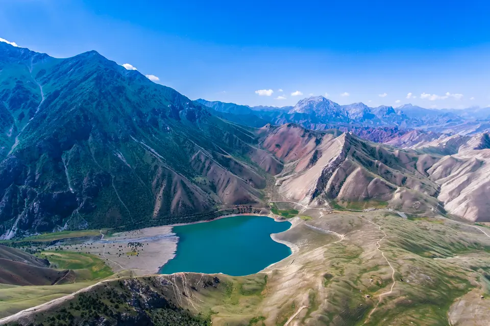 Mountain valley with a turquoise lake under a bright blue sky.