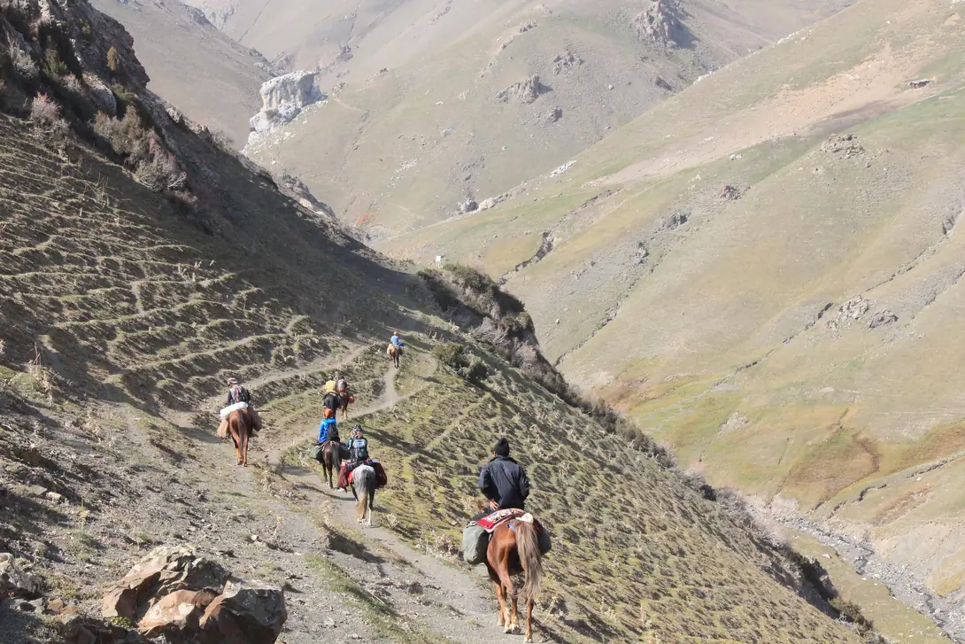 Chaarcha pass in Arslanbob with horseback riders riding down the canyon