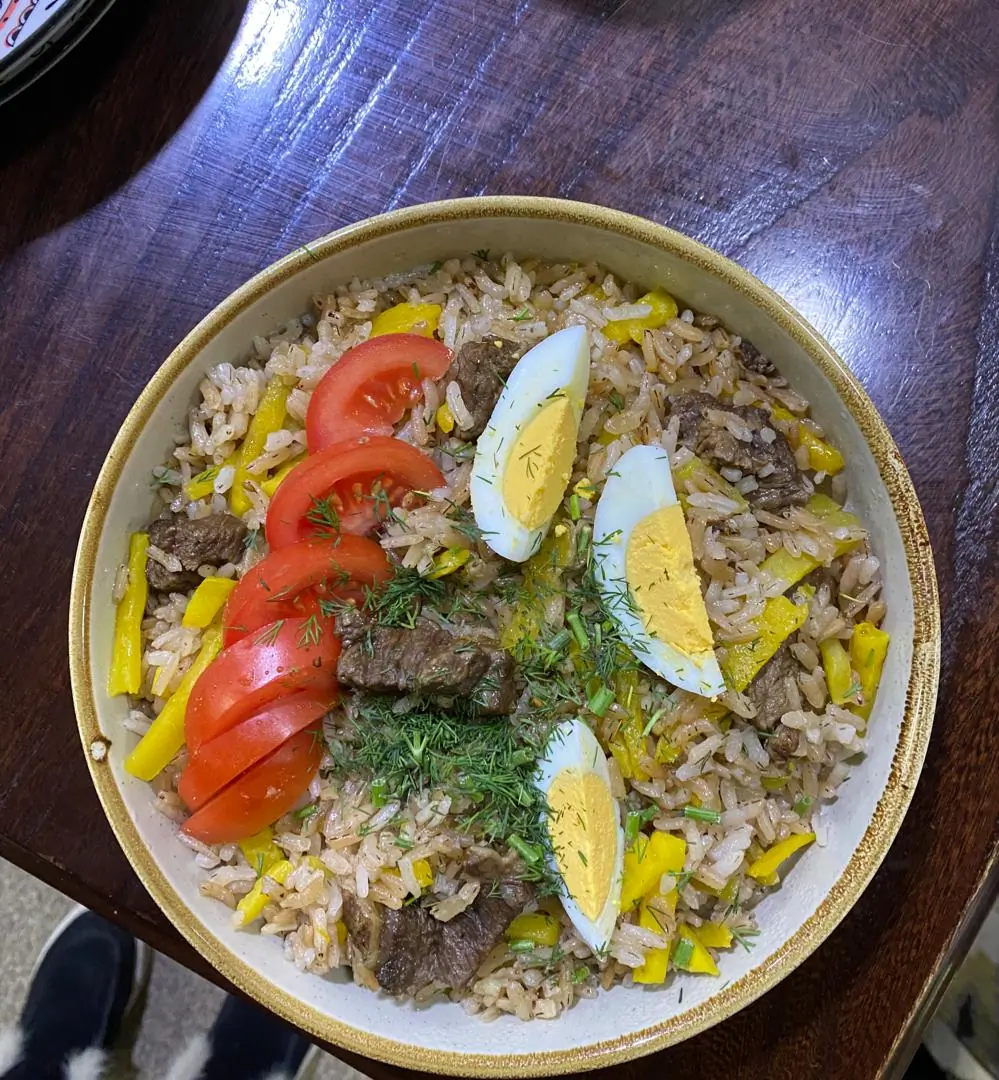 Rice pilaf in a plate with tomatoes and boiled eggs as decoration
