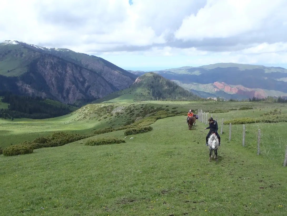 Horse riders riding from Kök Jayik meadows to Yrdyk meadows, we can see on the right side red rocks of Jeti Oguz "7 bulls"