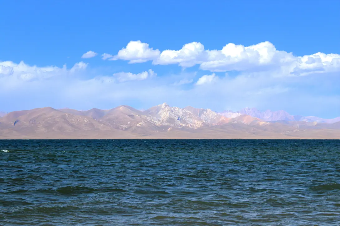 View of Ak-Tash mountain which means "White stone"  backside of the deep blue lake of Song Kul with blue sky and some with clouds