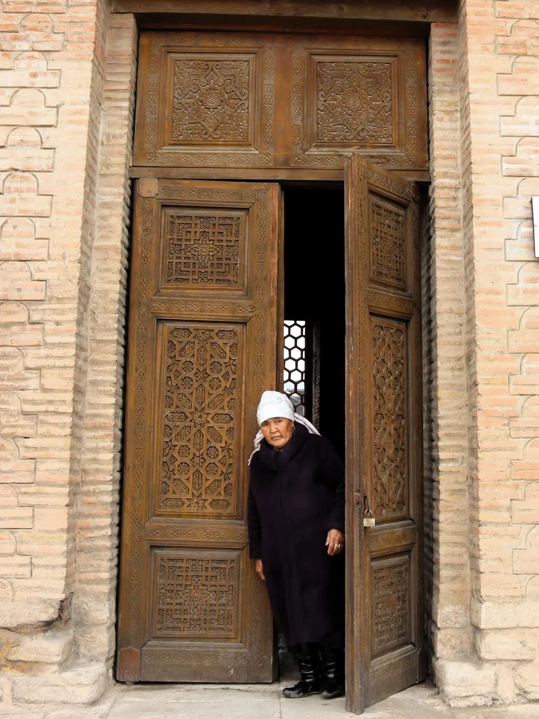 The wooden and carved door of the middle mausoleum of Uzgen with Kyrgyz woman